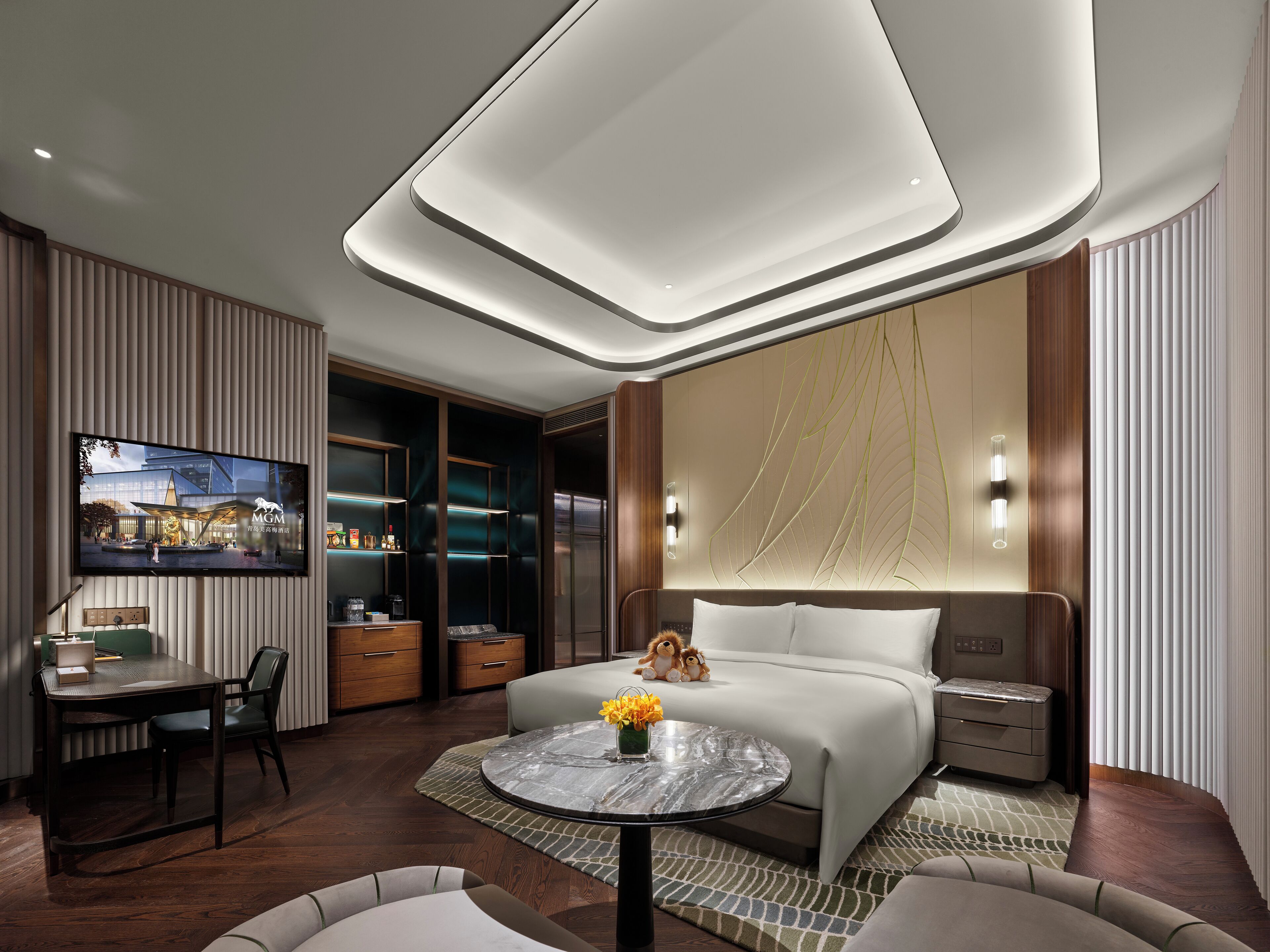 Habitación de hotel moderna con una cama grande, un escritorio y un televisor que muestra un paisaje urbano.