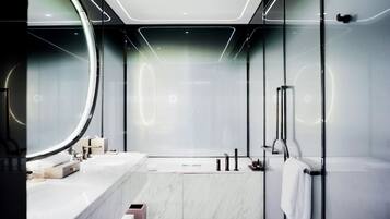 A modern bathroom with a large mirror, a bathtub, and a glass-enclosed shower area.