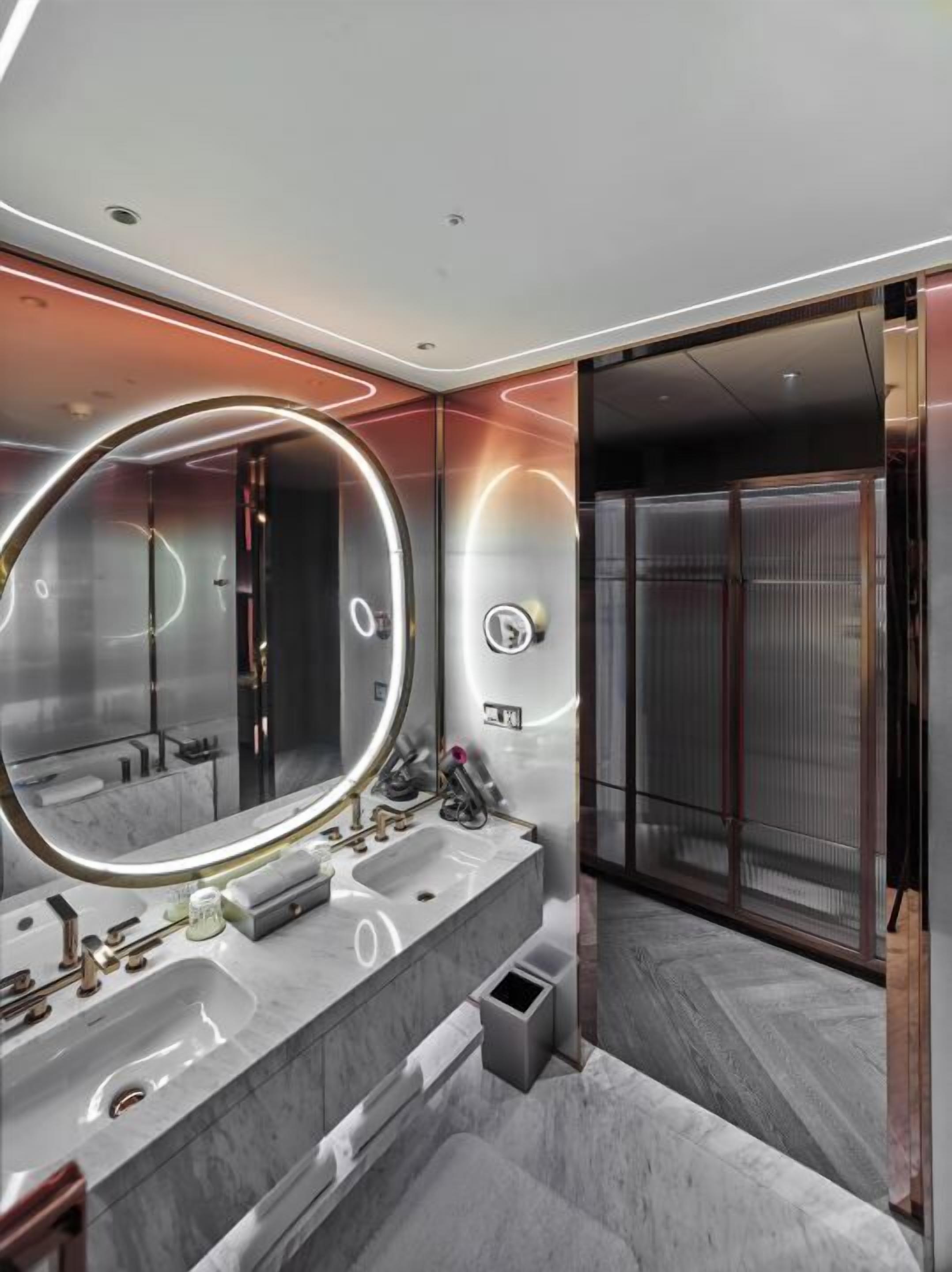 A modern bathroom with a large mirror, marble countertops, and a walk-in shower.