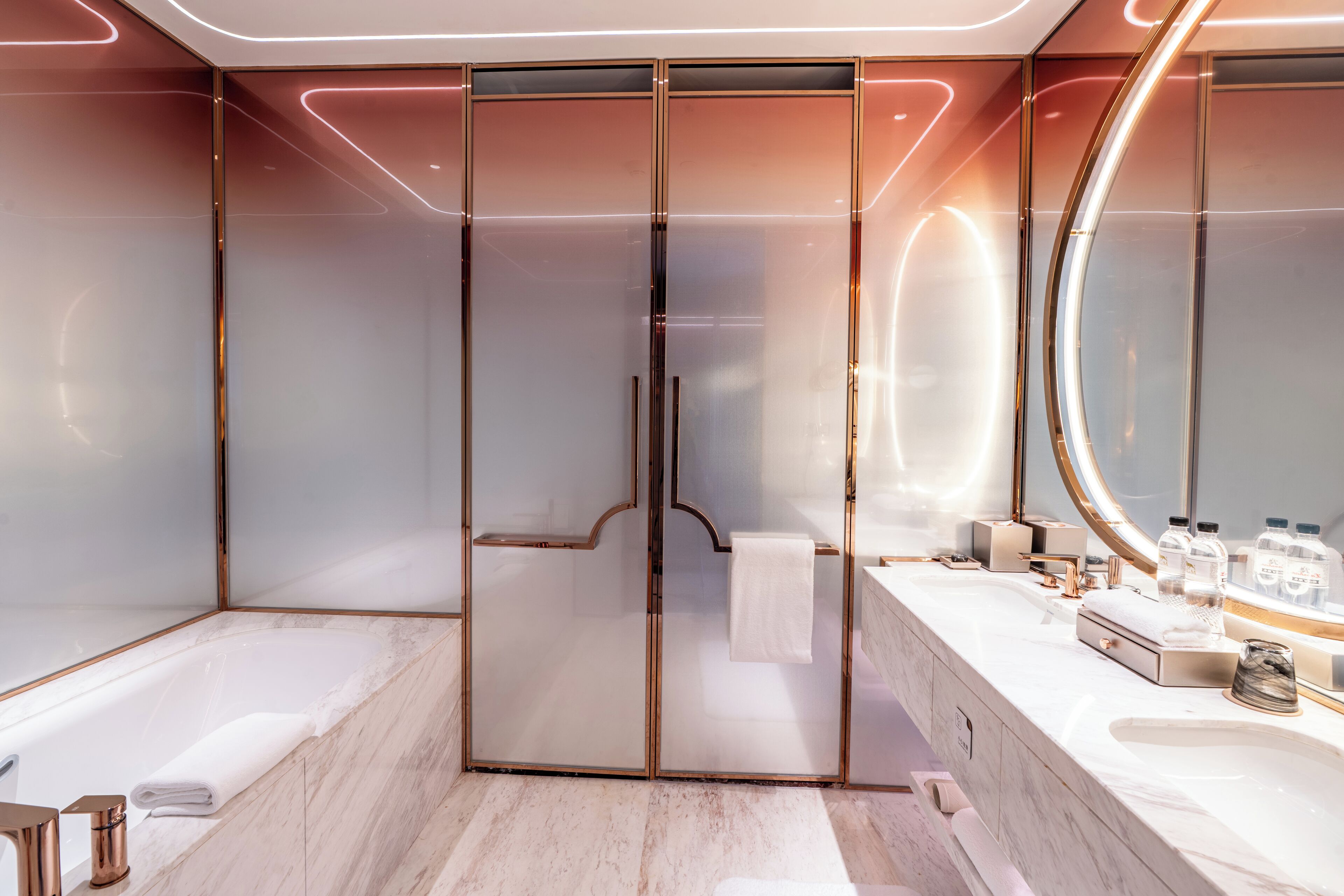 Un baño moderno con ducha envuelta en vidrio, un espejo grande y encimera de mármol.