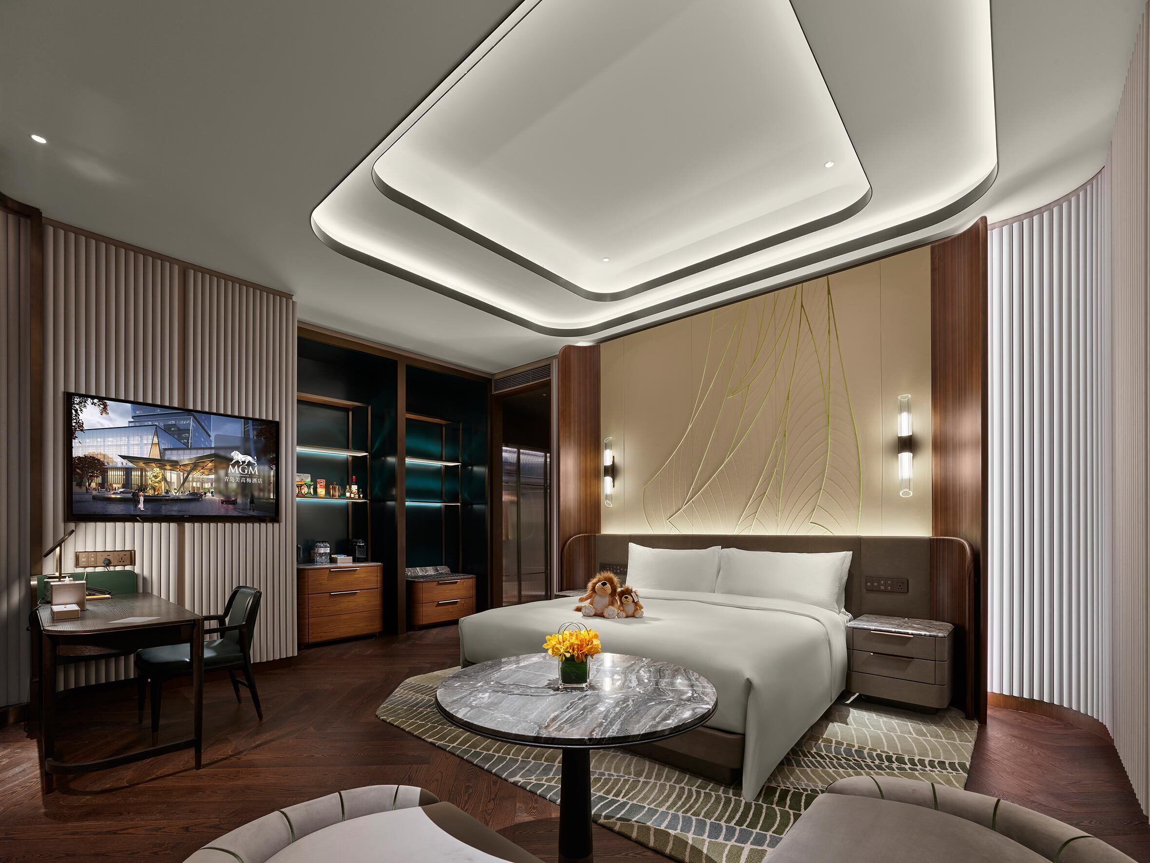 Ein modernes Hotelzimmer mit einem großen Bett, einem Schreibtisch und einem an der Wand befestigten Fernseher.