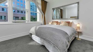Una camera d'albergo moderna con un letto grande, un comodino con una lampada, una grande finestra con tende e uno specchio a parete.