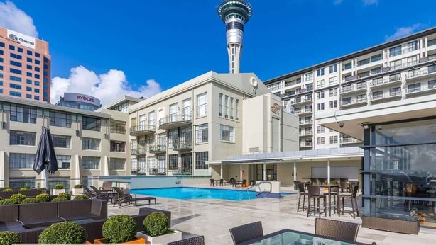 Un hotel con piscina sul tetto, area salotto all'aperto e vista su una torre.