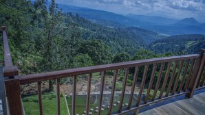 Una terraza de madera con vistas a un valle verde exuberante y montañas distantes.
