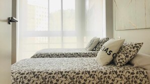 Un dormitorio con dos camas, un ventanal grande y una obra de arte colgada en la pared.