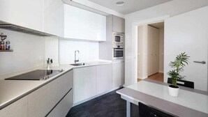 Una cocina moderna con armarios blancos, microondas integrado y un lavamanos.