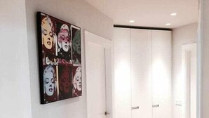 Un pasillo con una obra de arte grande en la pared, una puerta blanca y un armario con puertas correderas.