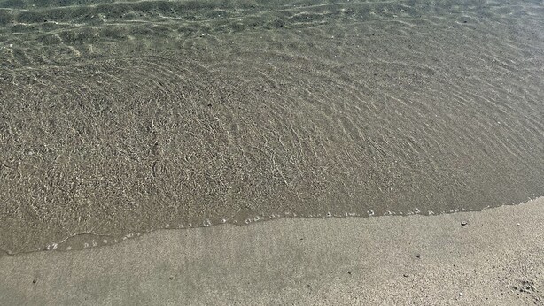 Una playa con aguas transparentes y poco profundas y una orilla arenosa.