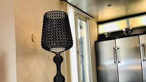Una cocina moderna con electrodomésticos de acero inoxidable, una silla negra y una lámpara de pie decorativa.