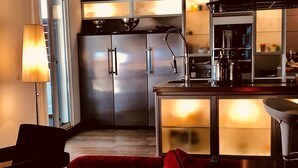 Una cocina moderna con electrodomésticos de acero inoxidable, una barra con fregadero, y un sofá rojo con cojines.