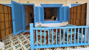 A room with a bed, a window with blue shutters, and a patterned floor. - Sadakham hotel (Luang Prabang)