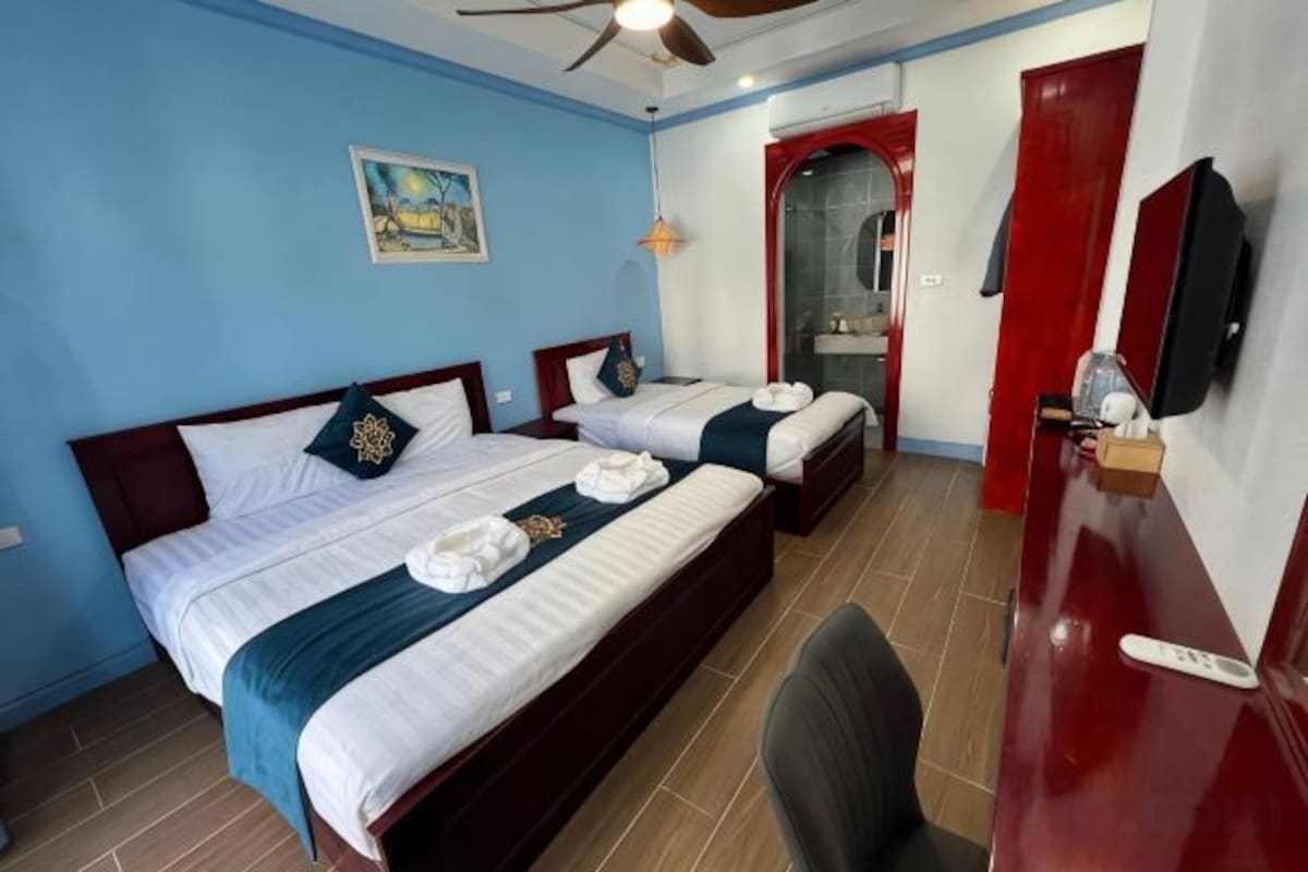 A hotel room with two beds, a desk, and a chair.