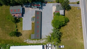 Luftaufnahme eines Grundstücks mit nummerierten Parkplätzen, einem Ferienhaus und einem Wohnhaus.
