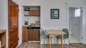 Une cuisine de taille réduite avec des meubles de rangement en bois, une table à manger avec deux chaises et un tableau accroché au mur.