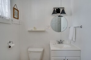 Ein Badezimmer mit Toilette, Waschbecken, Spiegel und zwei Wandleuchten.