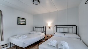 Een hotelkamer met twee eenpersoonsbedden, een klein nachtkastje met een lamp en een lijst aan de muur.