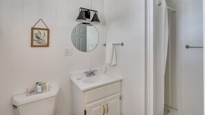 Een badkamer met toilet, wastafel, spiegel en handdoekhouder.