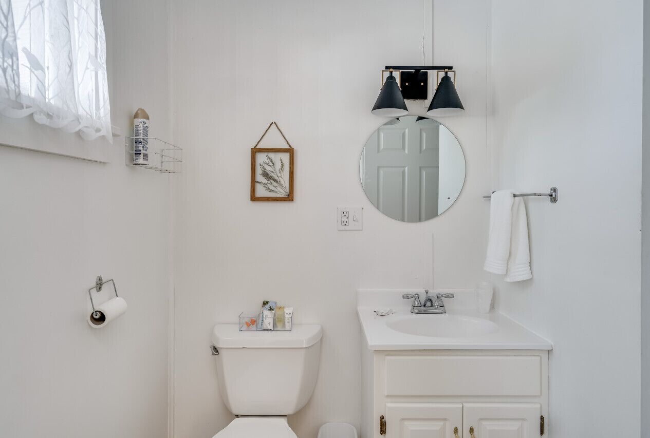Ein Badezimmer mit Toilette, Waschbecken, Spiegel und Handtuchhalter.