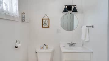 Ein Badezimmer mit Toilette, Waschbecken, Spiegel und Handtuchhalter.