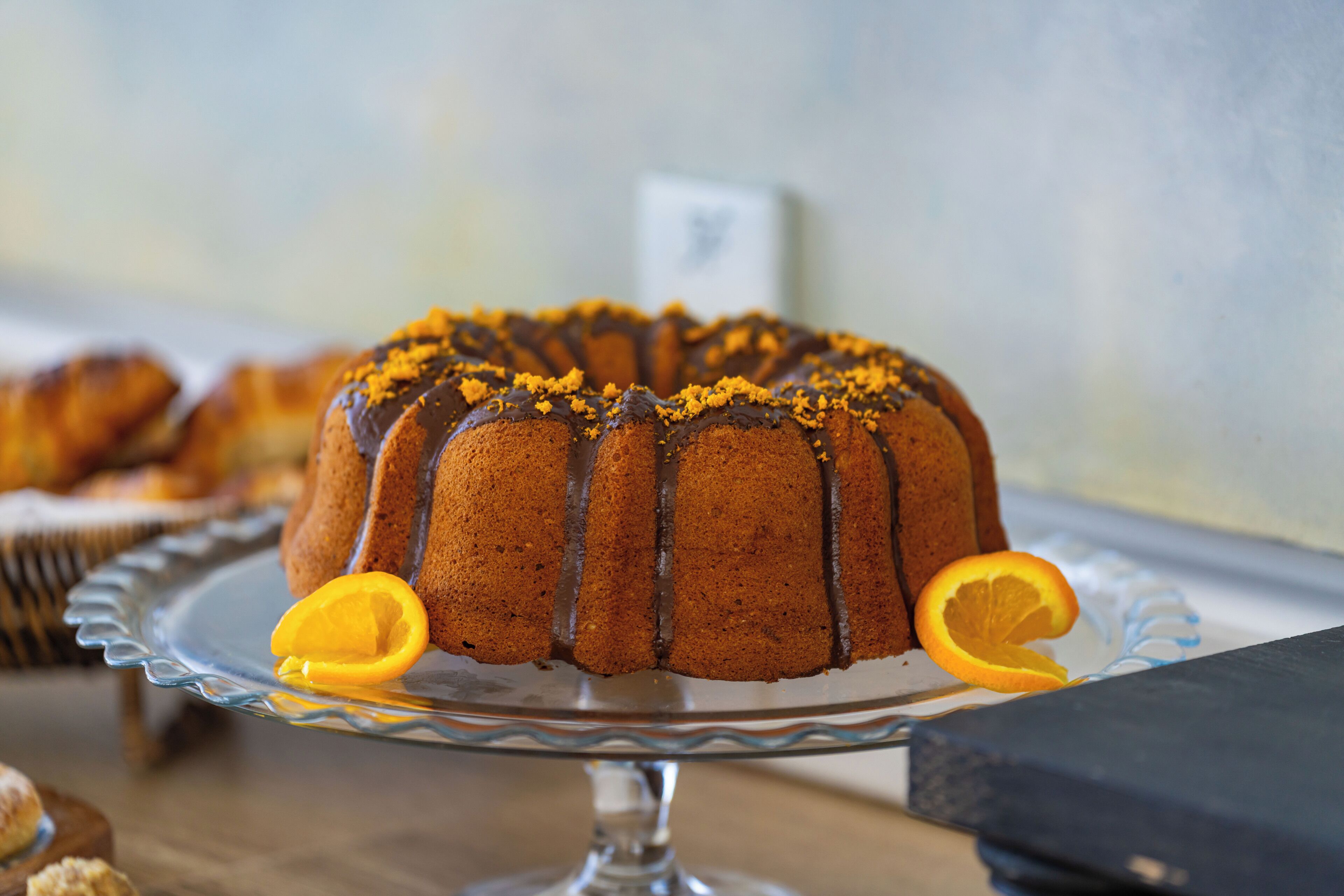 Ein Bundt-Kuchen auf einer Glaskuchenplatte, von dem eine Scheibe fehlt.