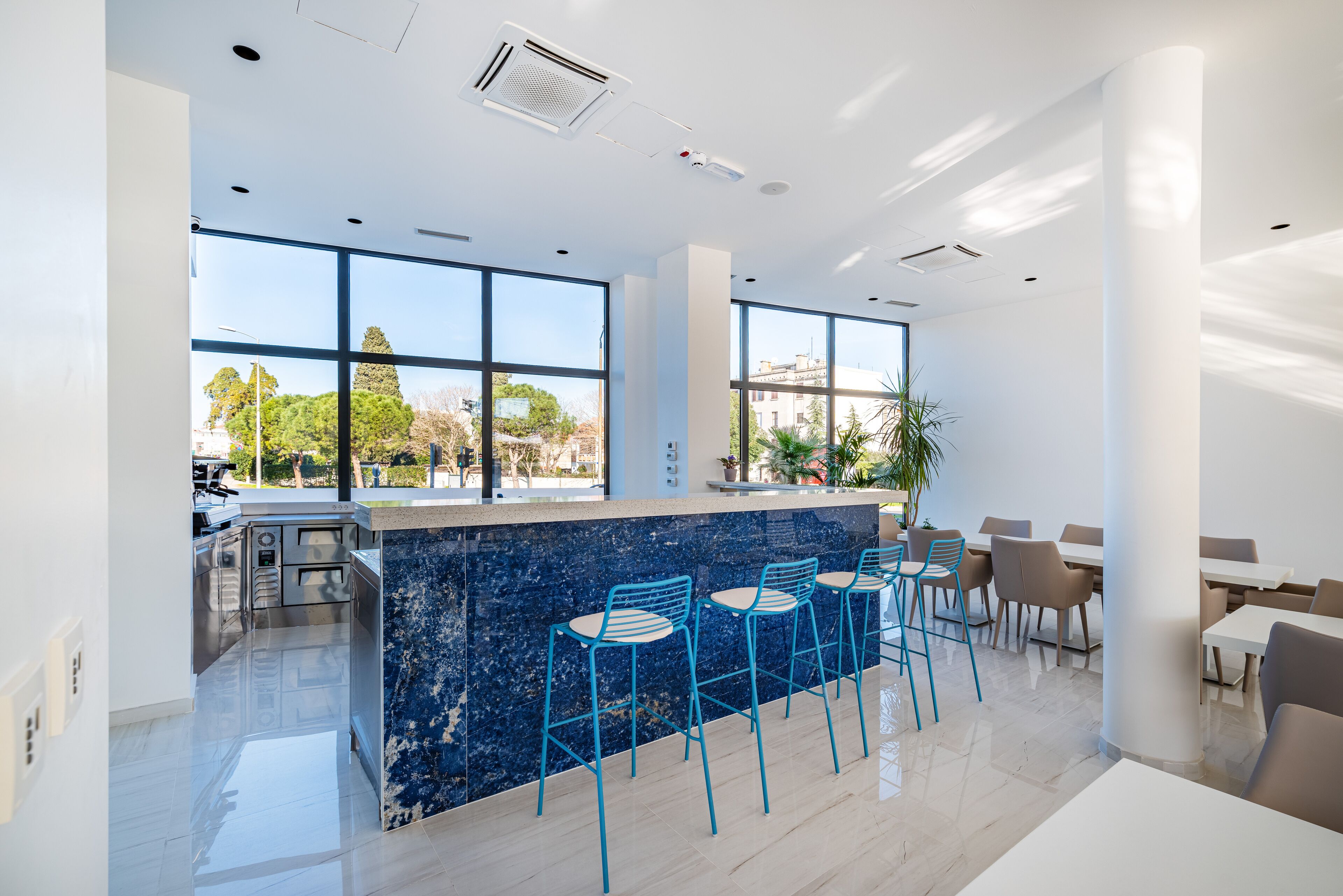 A modern kitchen with a marble island, bar stools, and a view of the city.