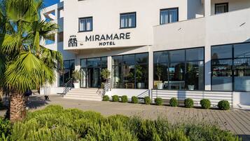Ein modernes Hotel mit auffälligem Schild, einer gepflegten Eingangspartie und einem angelegten Garten.