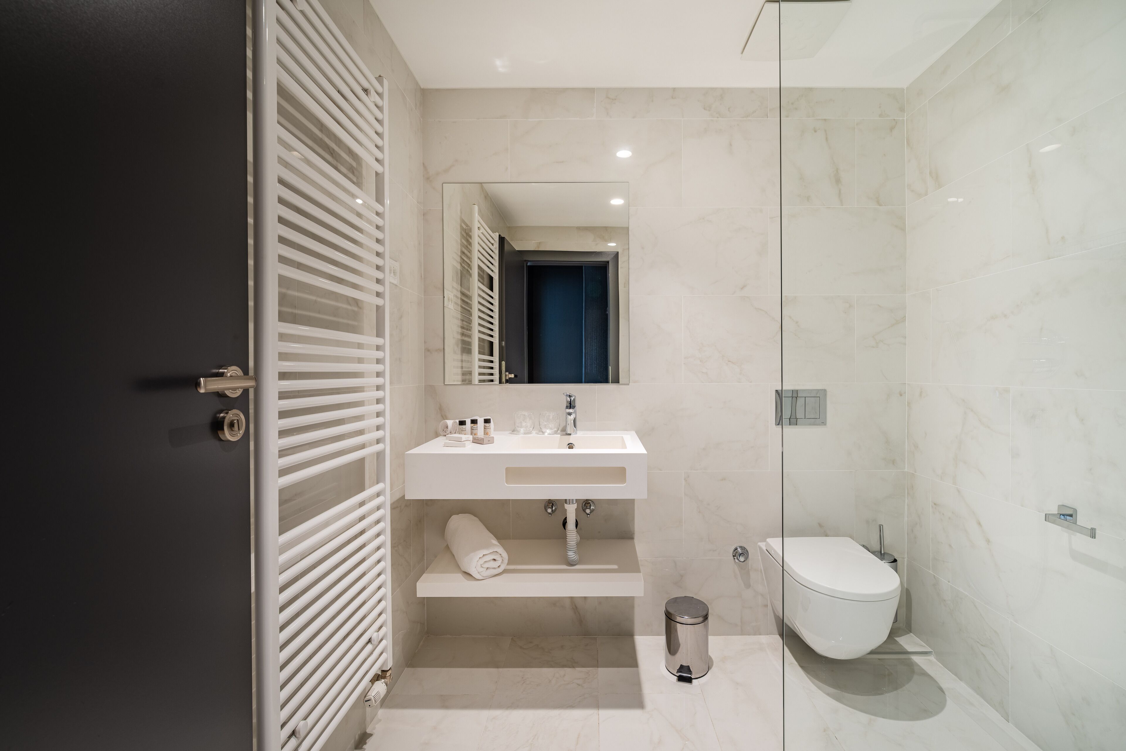 Een moderne badkamer met een wit wastafel, spiegel en toilet.