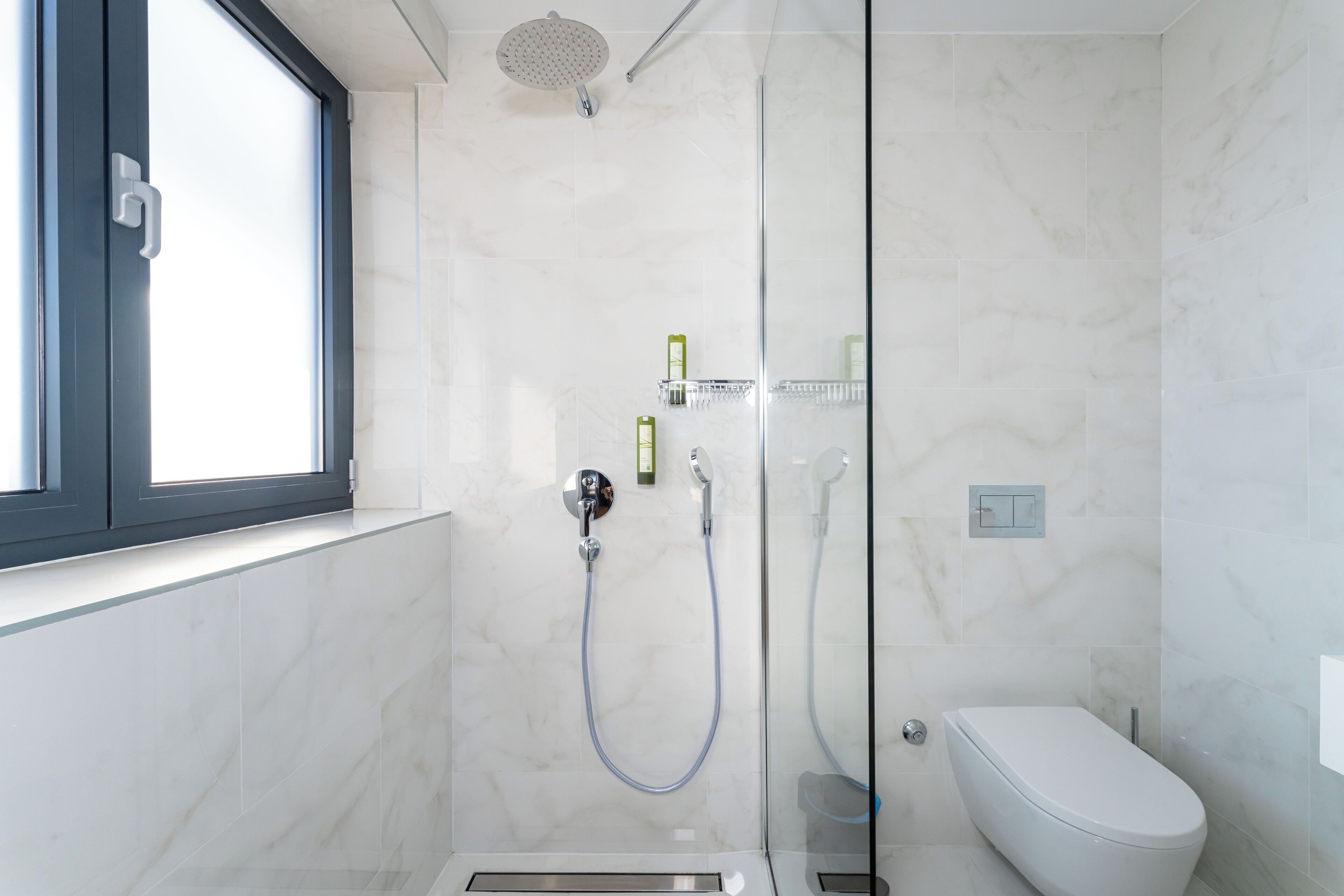 Un baño moderno con ducha de vidrio, inodoro y ventana.