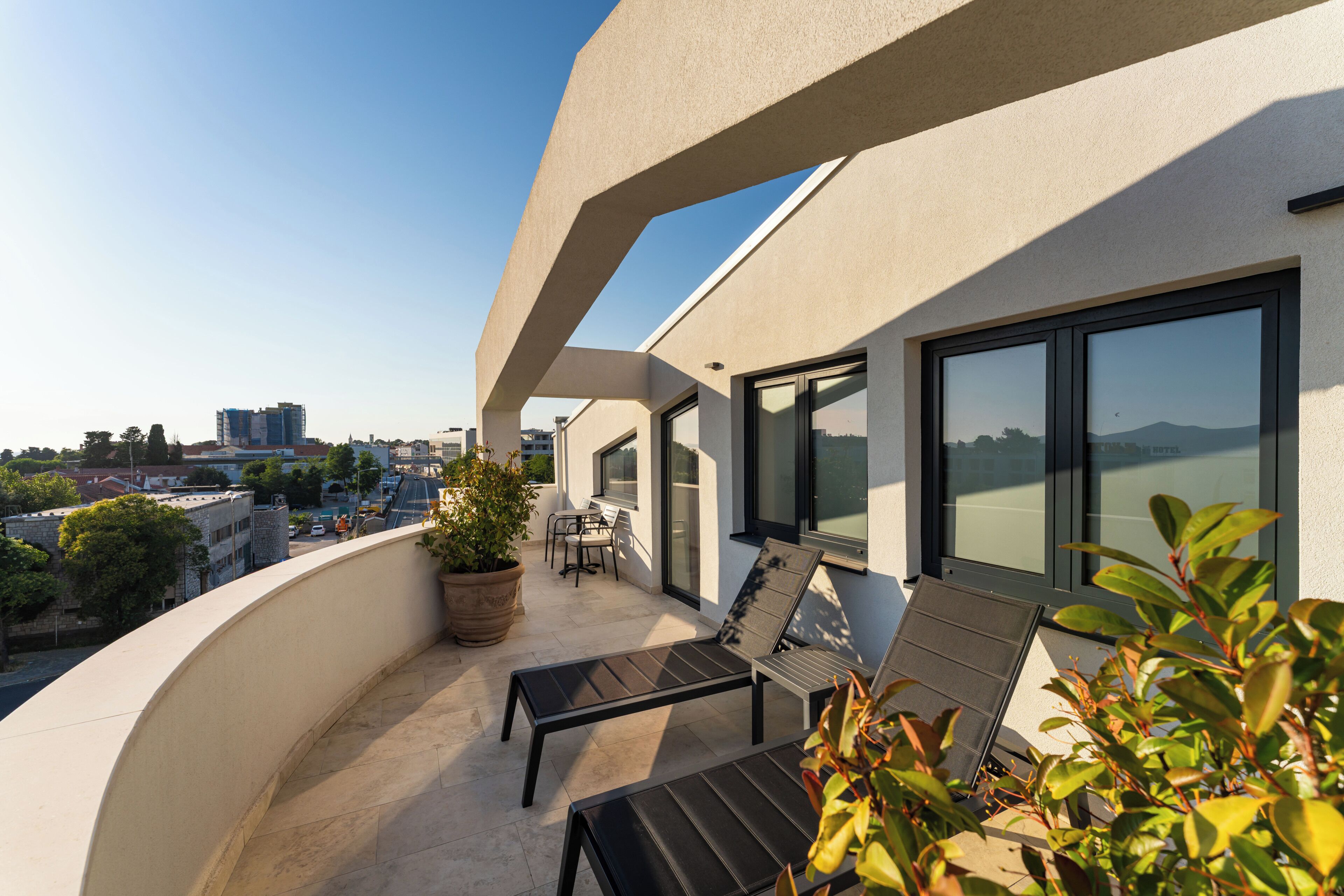 A balcony with a seating area, a potted plant, and a view of the cityscape.
