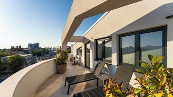 A balcony with a seating area, a potted plant, and a view of the cityscape.