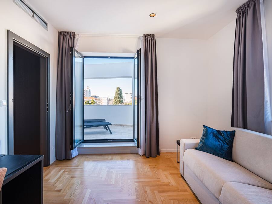 A modern living room with a sofa, a small table, and a bench outside a sliding glass door.