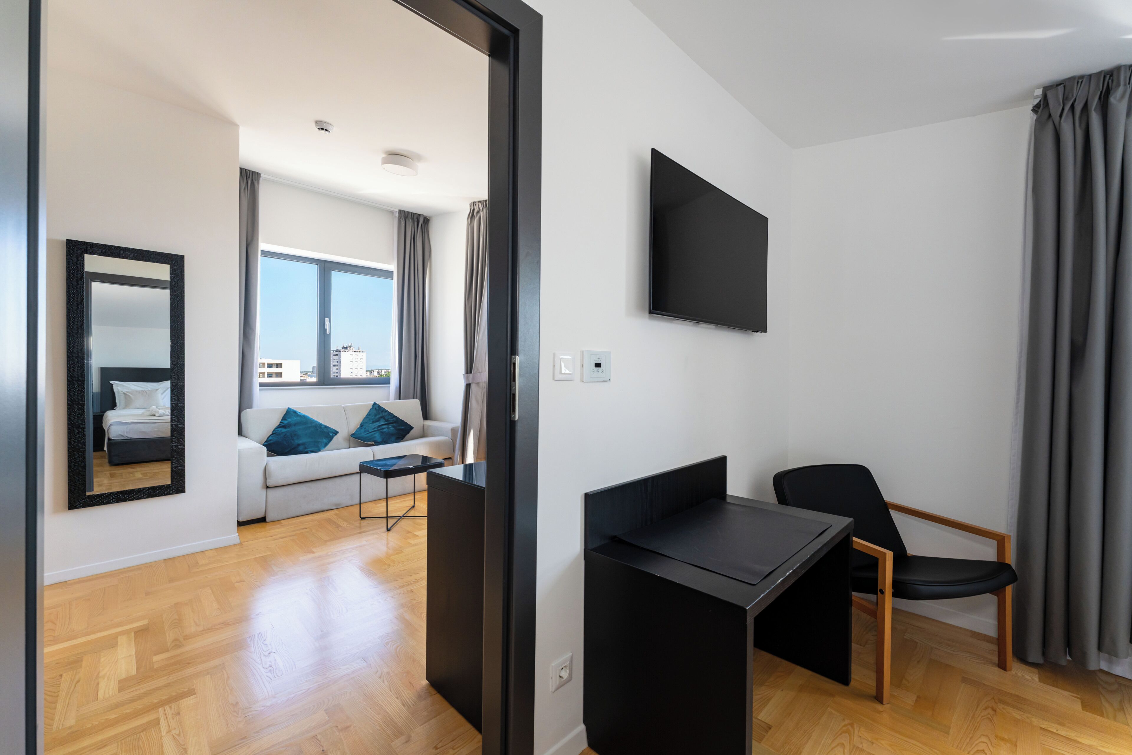 Een moderne woonkamer met een bank, een salontafel, een aan de muur bevestigde televisie en een fauteuil.