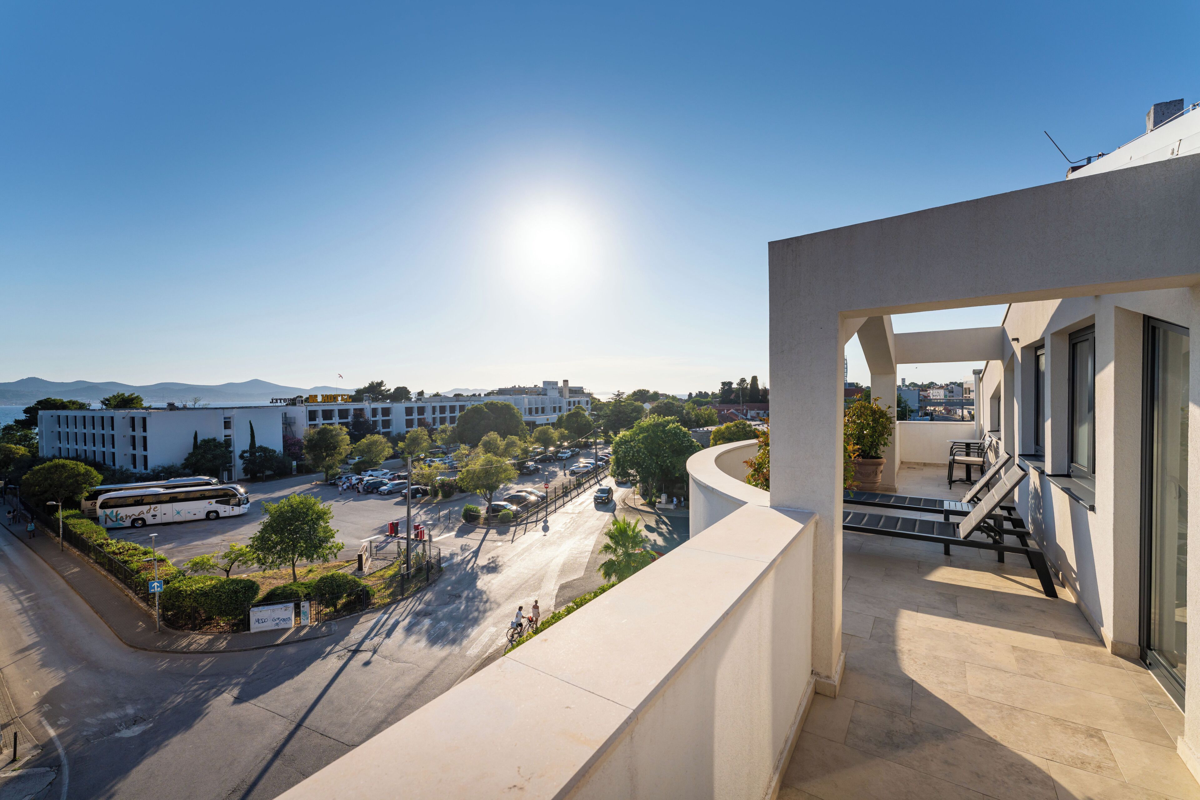 A modern building with a balcony overlooking a parking area and a clear view of the surrounding cityscape.