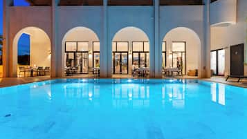 Una piscina con un bar y una zona de estar al fondo.