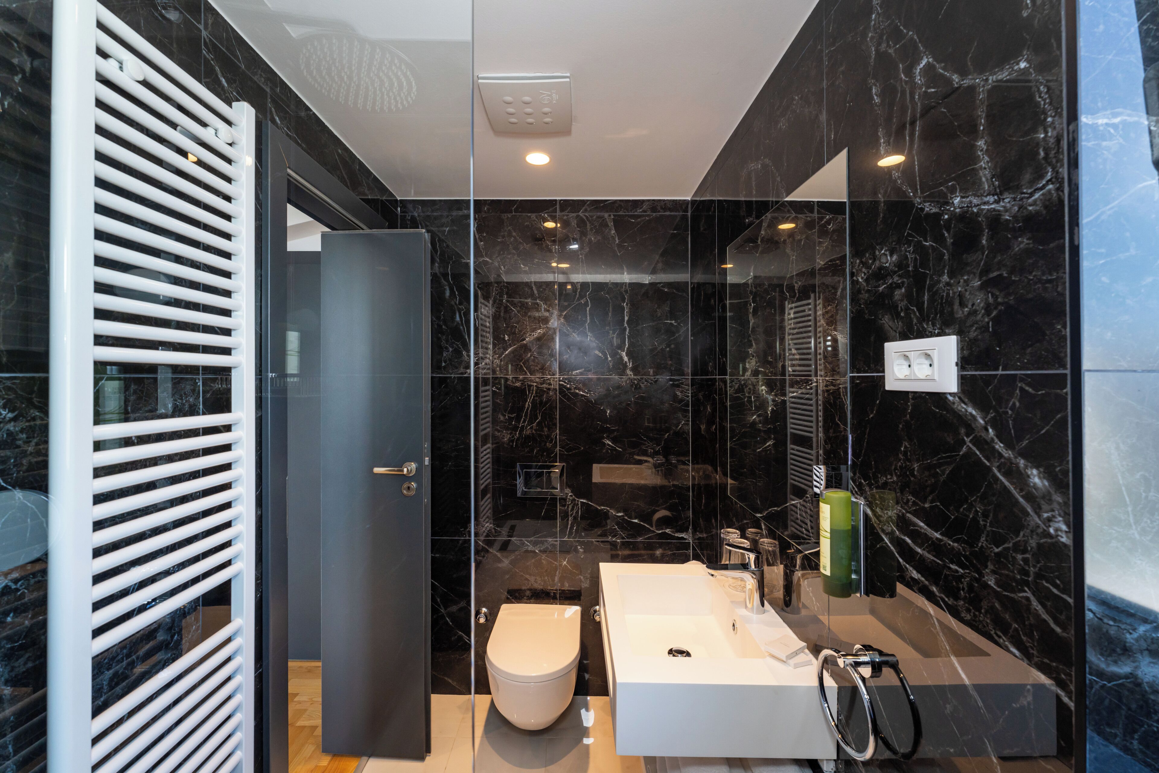 Een moderne badkamer met een groot, wit bad, een toilet en een douchehoek.