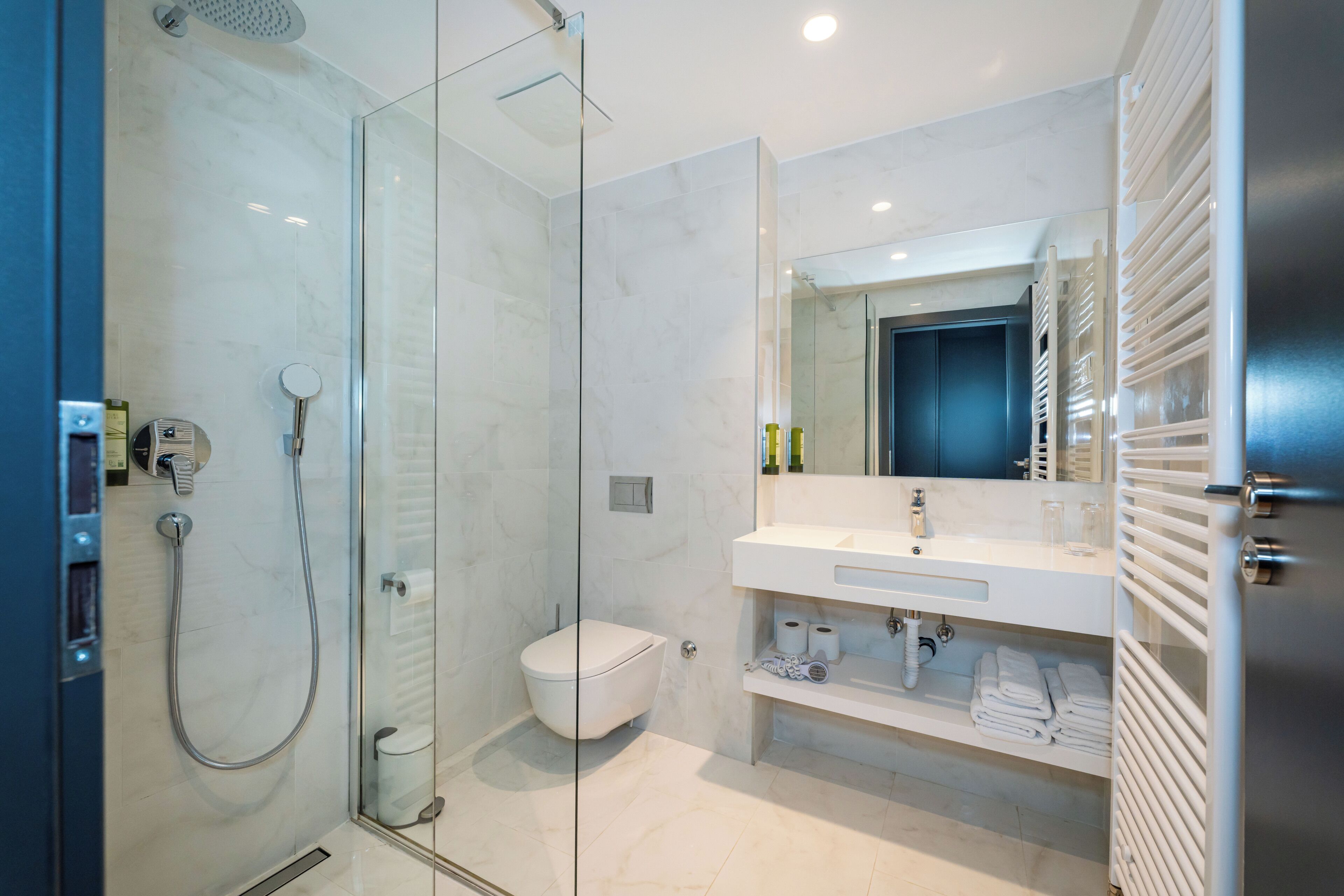 A modern bathroom with a glass-enclosed shower, a white toilet, and a vanity with a mirror.
