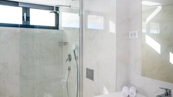 Une salle de bain moderne avec une douche à parois de verre, un lavabo blanc et un grand miroir.