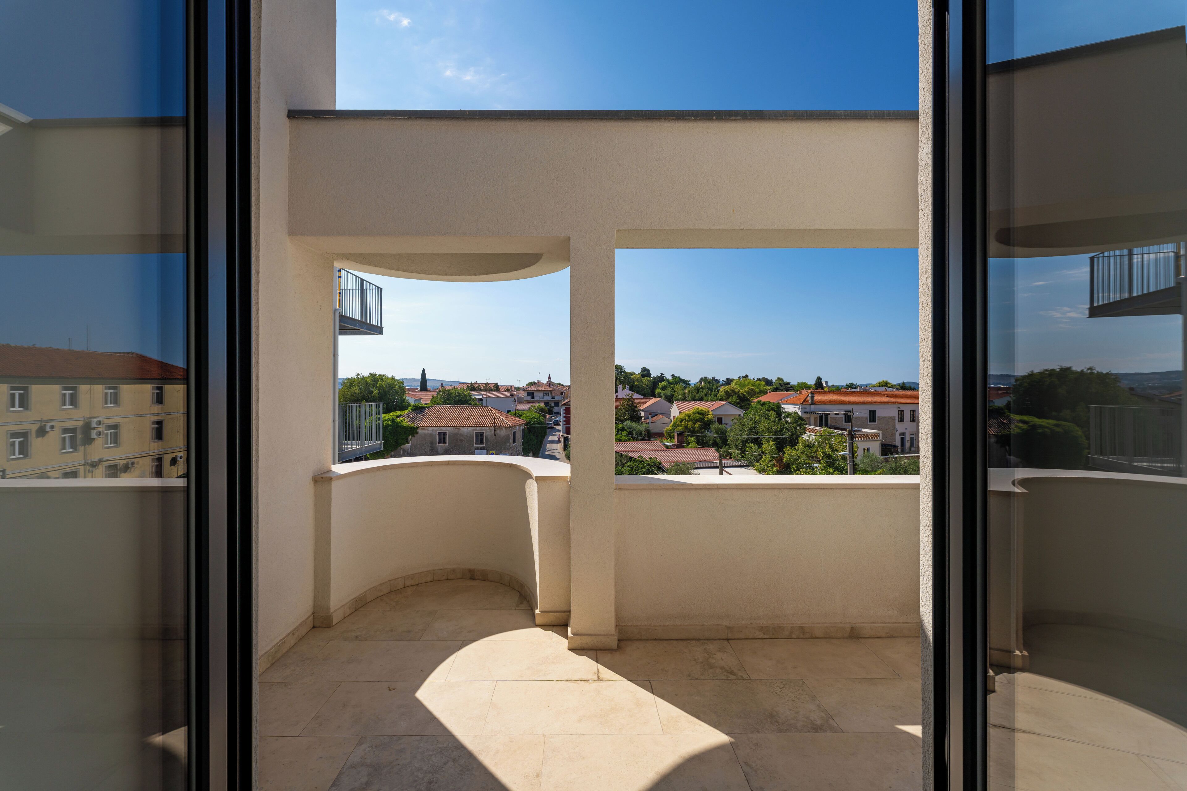A balcony with a clear view of a residential area, including houses and trees.