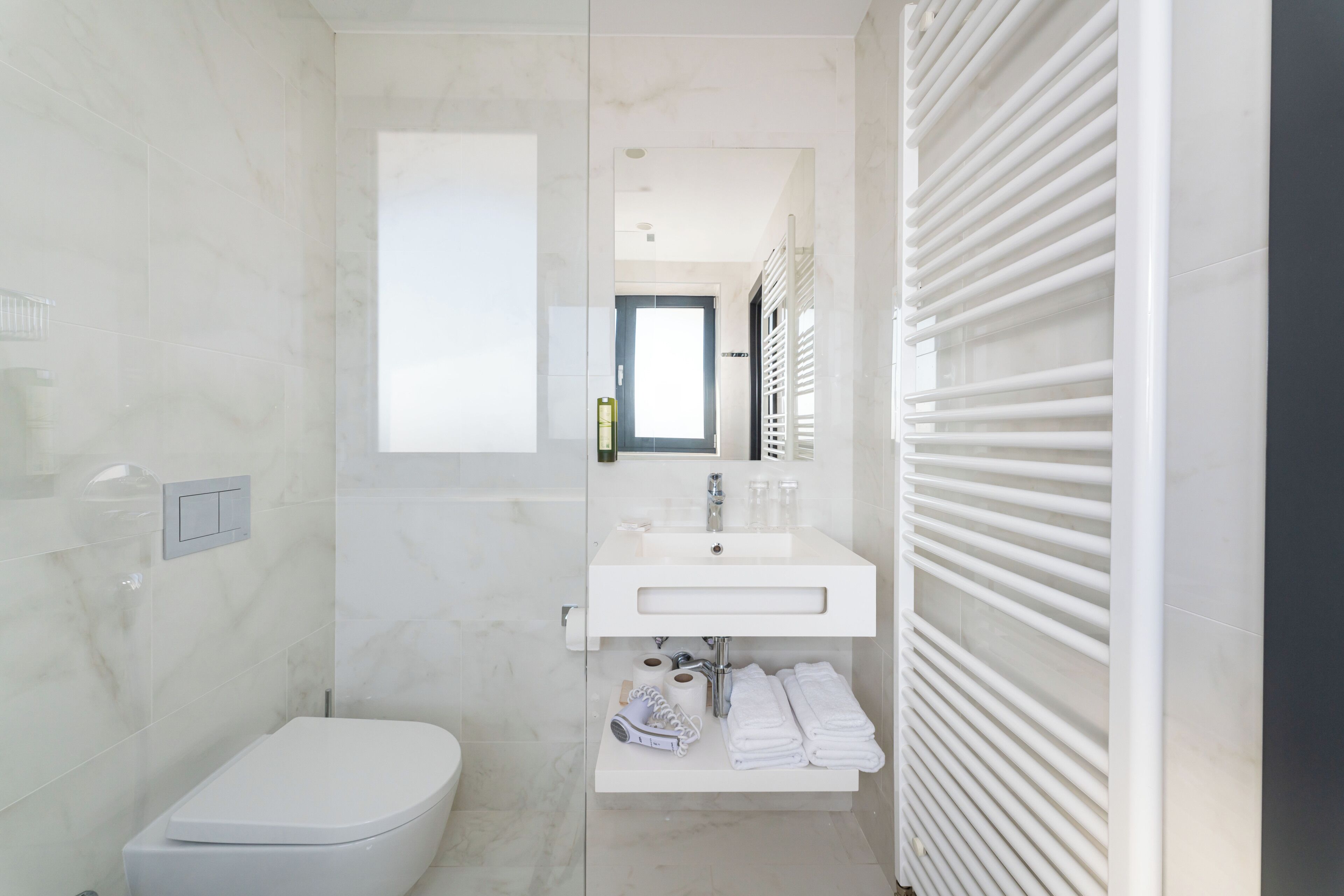 A modern bathroom with a toilet, sink, and towel rack.
