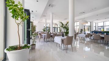 Un comedor interior amplio con techos altos, ventanas grandes y muebles modernos.