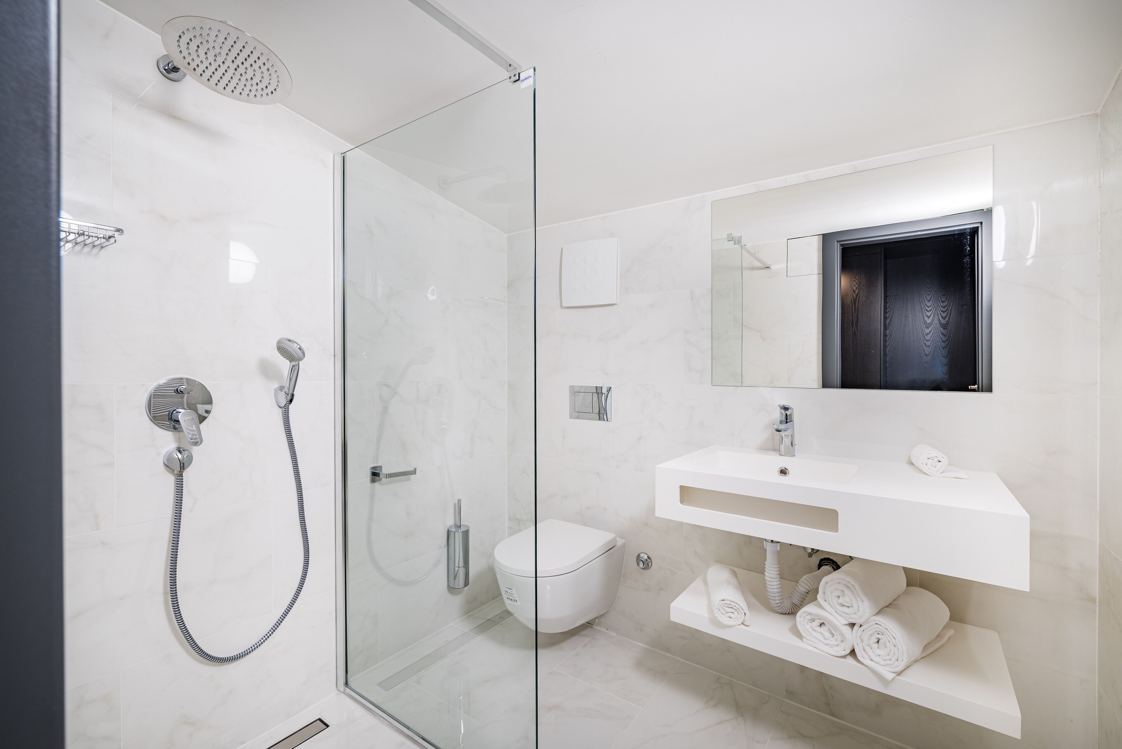 A modern bathroom with a glass shower enclosure, a white sink with a mirror, and a toilet.