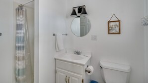 Un baño con un lavamanos blanco, un espejo, un inodoro y una cortina de ducha.