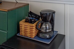 A coffee maker on a mat next to a basket of coffee pods.