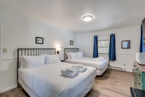 Une chambre d’hôtel avec deux lits, une commode, un four à micro-ondes et une fenêtre avec des rideaux.