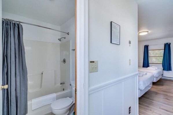 Ein Badezimmer mit Dusche, Toilette und einem kleinen Bett mit Handtuch.