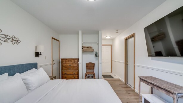 Ein Schlafzimmer mit einem großen Bett, einem Schminktisch, einem Sessel, einem Fernseher und einer Mikrowelle.