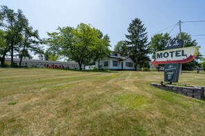 A motel with a signboard, a lawn, and a building in the background.