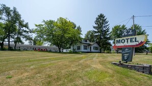 A motel with a large sign, a lawn, and trees in the background. - K's Motel with Stunning St. Lawrence River Views - Room 9 (Clayton)
