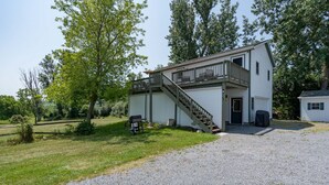 A two-story building with a balcony on the upper floor, a front door, and a small attached garage. - K's Motel with Stunning St. Lawrence River Views - Room 9 (Clayton)