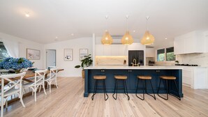 Una cocina moderna con una isla central, taburetes de bar e iluminación colgante.
